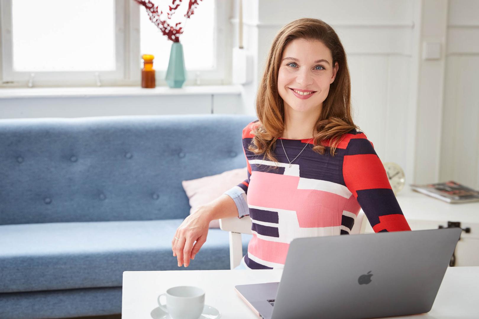 Personal Branding Shooting: Eine Frau sitzt an einem Laptop in einem hellen Studio und schaut nach oben. Die moderne, minimalistische Umgebung unterstreicht ihre professionelle Ausstrahlung.